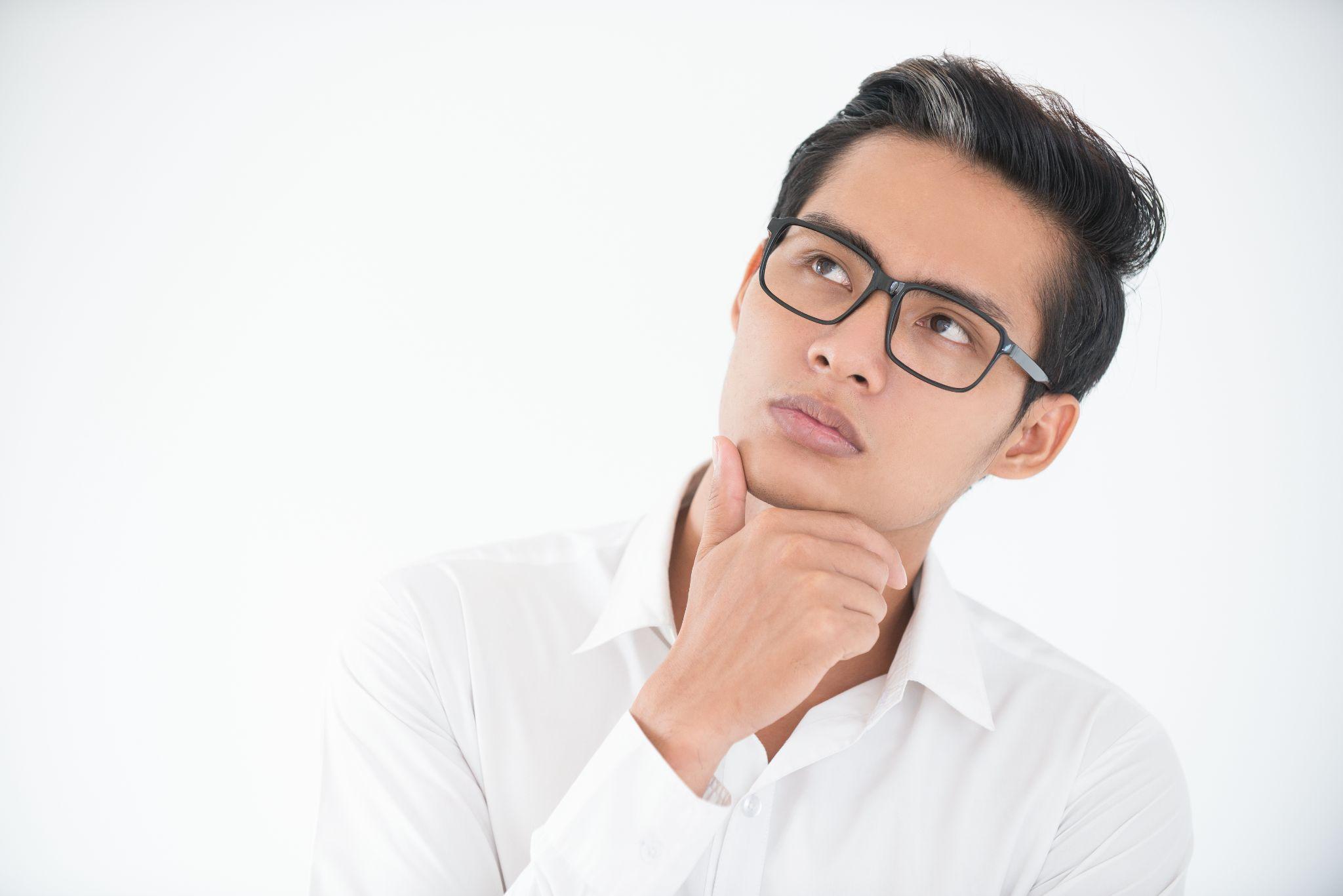 Young asian businessman looking up while thinking
